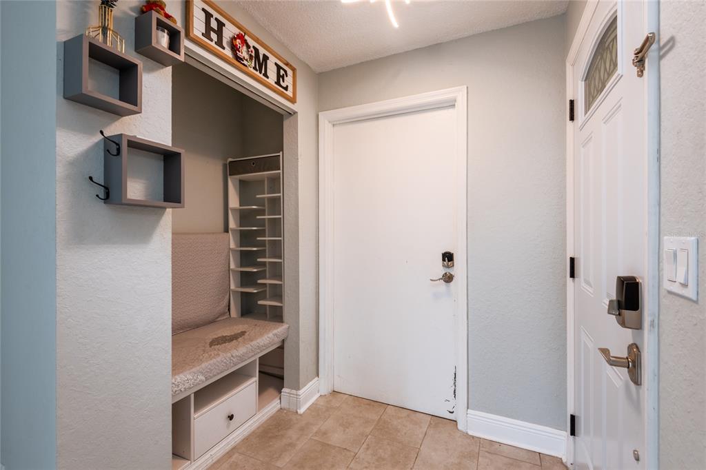 An entryway features a built-in bench with shoe storage, wall-mounted shelves, and a white door — 1944 ELAINE DRIVE UNIT 1944, CLEARWATER, FL
