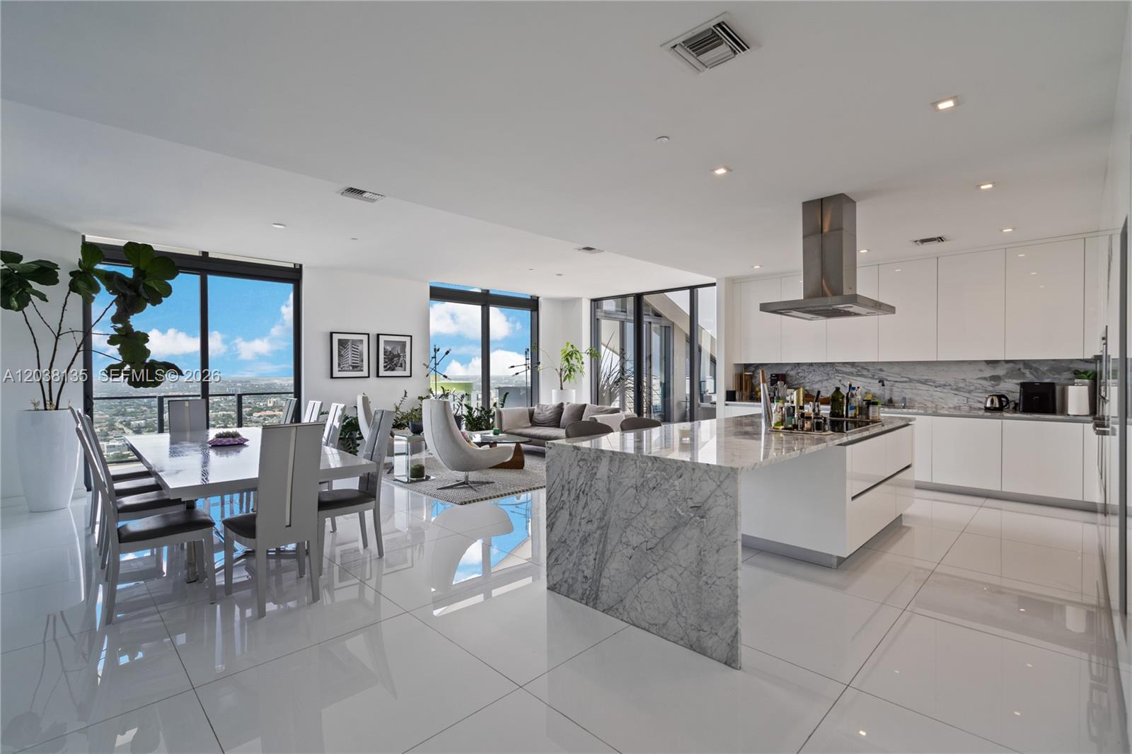 A modern open-concept kitchen and dining area features white cabinetry, marble surfaces, and floor-to-ceiling windows — 88 SW 7th St # 4203, Miami FL 33130, MIAMI, FL