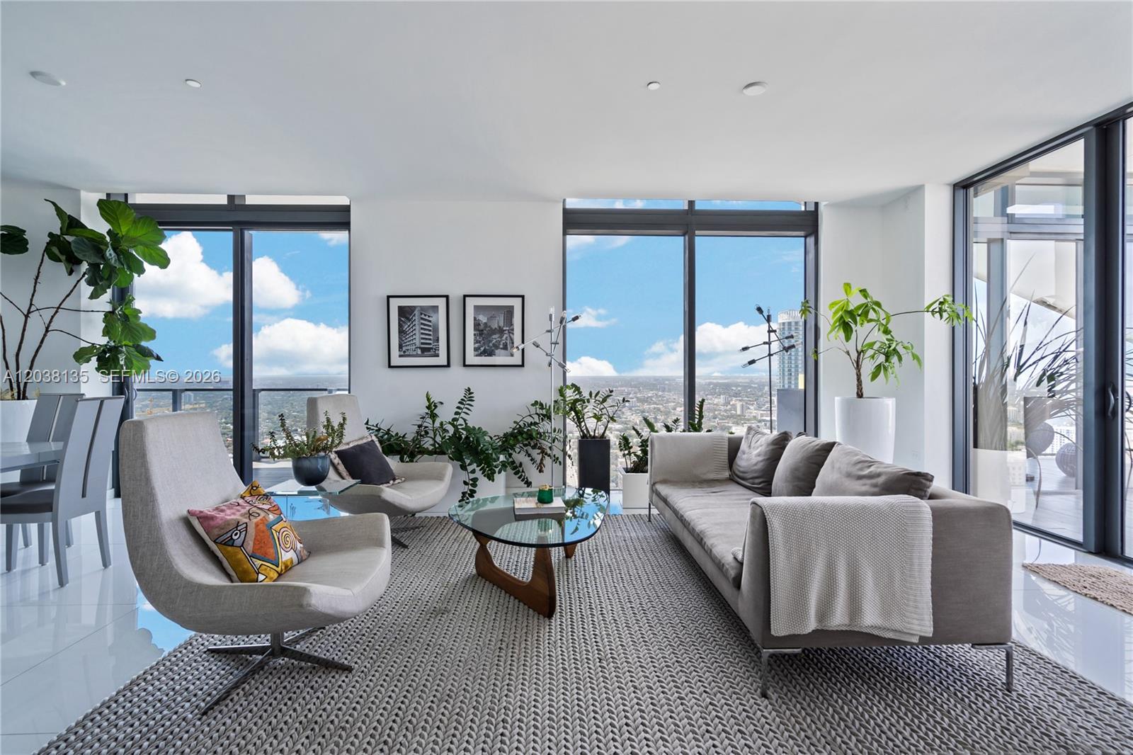 A modern living room features floor-to-ceiling windows, a gray sofa, and two accent chairs — 88 SW 7th St # 4203, Miami FL 33130, MIAMI, FL