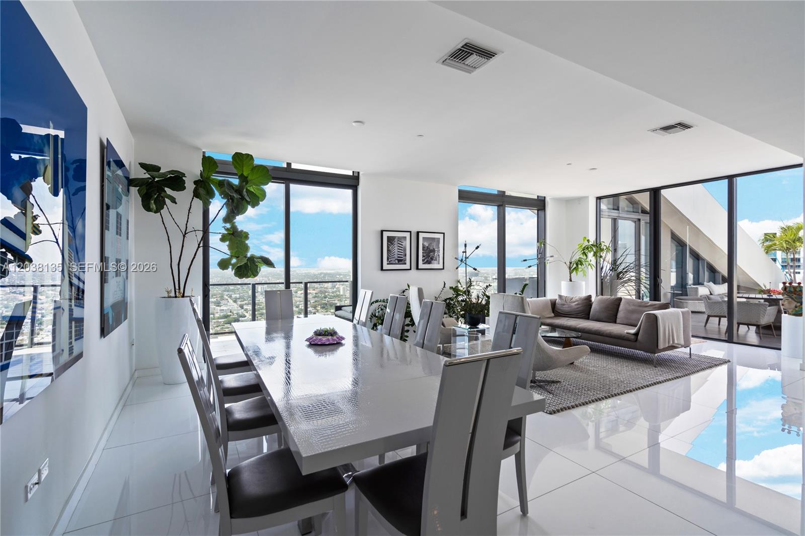 A modern dining and living area features white tile floors, floor-to-ceiling windows, and city views — 88 SW 7th St # 4203, Miami FL 33130, MIAMI, FL