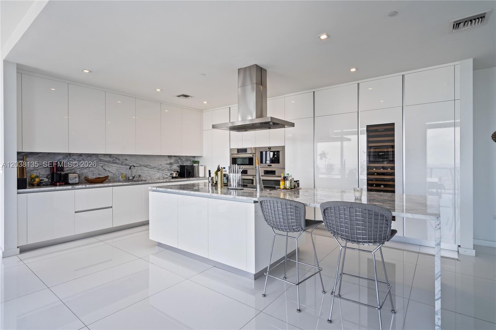 A modern white kitchen features a marble island, stainless steel appliances, and gray bar stools — 88 SW 7th St # 4203, Miami FL 33130, MIAMI, FL
