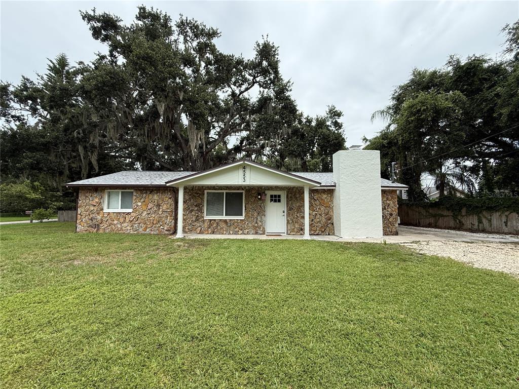 A single-story house with a stone facade, white chimney, and a covered front porch — 3019 LLOYD DRIVE, HOLIDAY, FL
