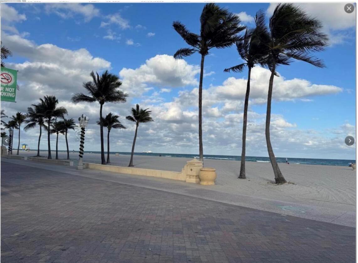 A paved boardwalk runs alongside a sandy beach with palm trees under a cloudy sky — 323 Monroe Street # 6, Hollywood FL 33019, HOLLYWOOD, FL