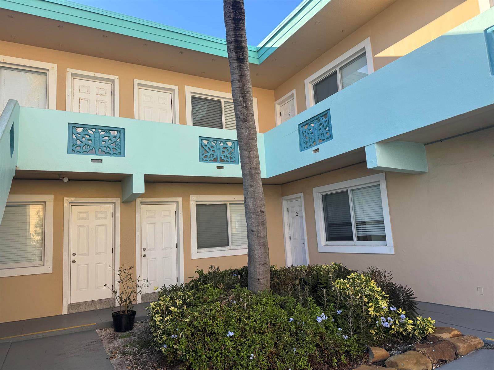 A two-story apartment building exterior features tan walls, light blue trim, and a central palm tree — 323 Monroe Street # 6, Hollywood FL 33019, HOLLYWOOD, FL