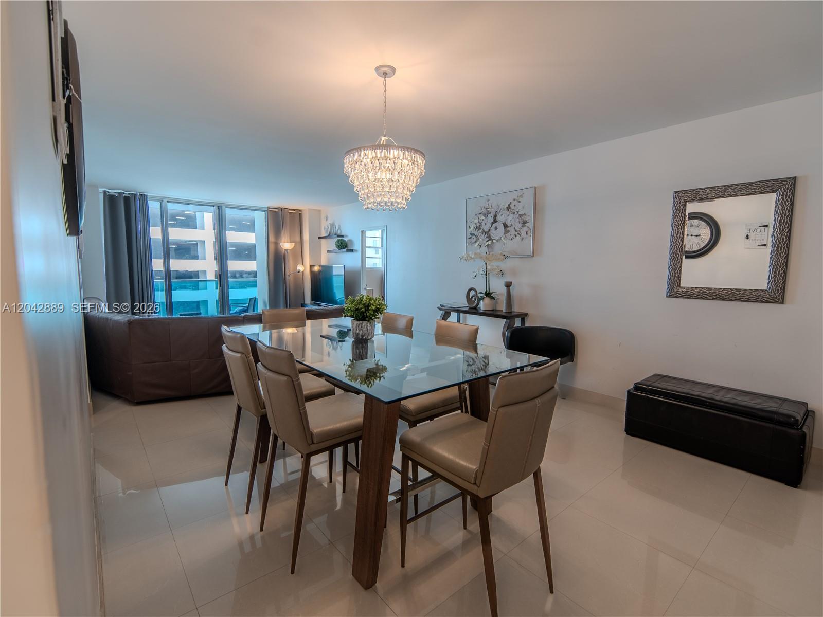 A dining area features a glass-topped table, six chairs, and a crystal chandelier — 4001 S Ocean Dr # 8J, Hollywood FL 33019, HOLLYWOOD, FL