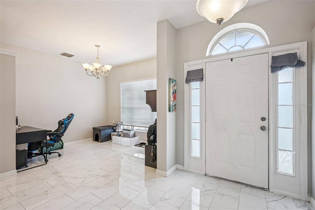 A bright entryway features white marble-look tile flooring, a chandelier, and a home office area — 13805 EAGLES GLEN COURT, ORLANDO, FL
