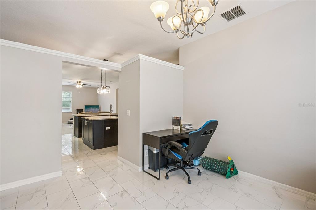 A home office desk and gaming chair sit in a tiled room near a kitchen — 13805 EAGLES GLEN COURT, ORLANDO, FL