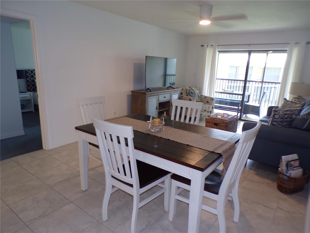 A dining area with a wooden table and white chairs sits before a living room — 1461 AQUI ESTA DRIVE UNIT B4, PUNTA GORDA, FL