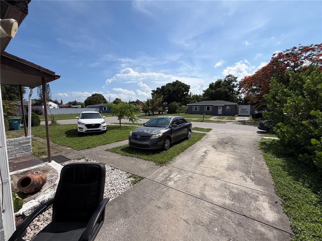 A view from a porch looking out at a driveway, two parked cars, and houses — 15331 NW 27TH PLACE, OPA LOCKA, FL