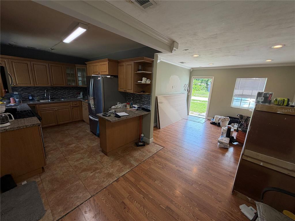 A kitchen with wood cabinets and tile flooring transitions into a living area with wood floors — 15331 NW 27TH PLACE, OPA LOCKA, FL