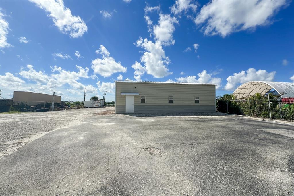 A single-story metal building stands on a paved lot under a bright blue sky — 2820 AVENUE OF THE AMERICAS, ENGLEWOOD, FL