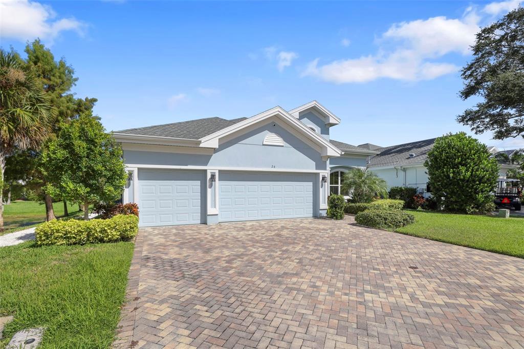 A light blue house with a three-car garage and a paved driveway under a blue sky — 26 CONCORD DRIVE, DUNEDIN, FL