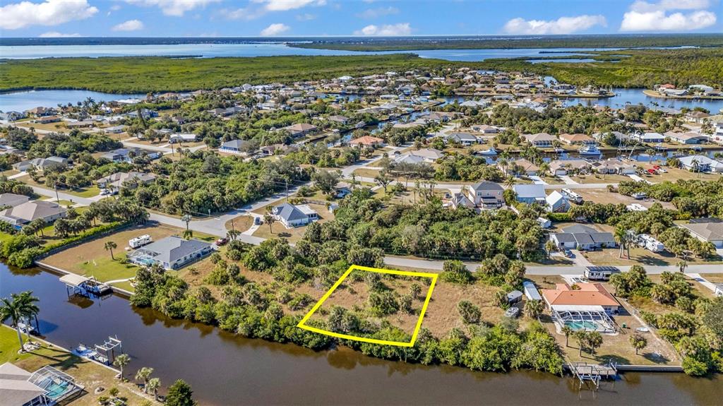 An aerial view shows a vacant, rectangular waterfront lot highlighted in yellow near residential homes — 4298 LIBRARY STREET, PORT CHARLOTTE, FL