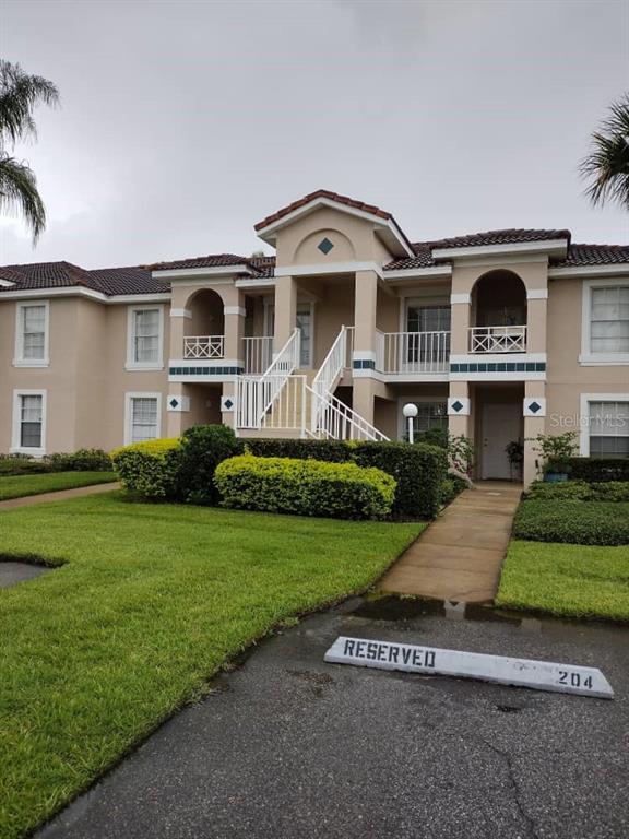 A two-story apartment building with beige stucco walls, a tiled roof, and exterior staircases — 13829 TIMBERLAND DRIVE UNIT 203, ORLANDO, FL