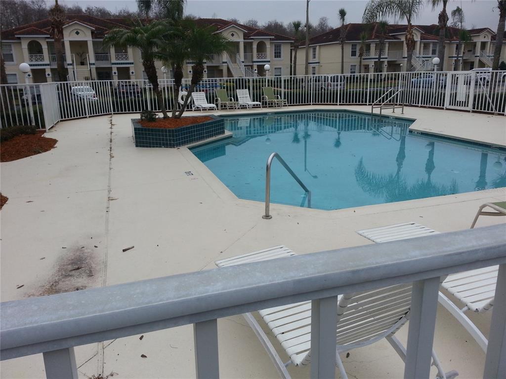 A swimming pool with a palm tree planter is surrounded by a white fence and chairs — 13829 TIMBERLAND DRIVE UNIT 203, ORLANDO, FL