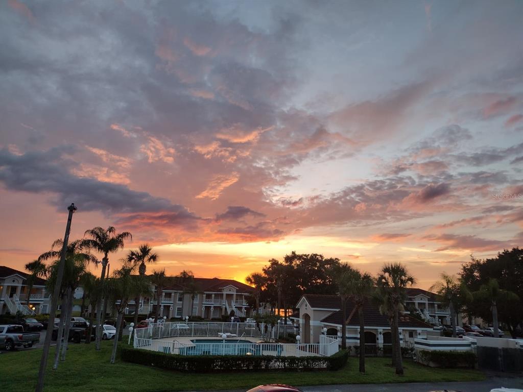 A view of a sunset over a community swimming pool and apartment buildings — 13829 TIMBERLAND DRIVE UNIT 203, ORLANDO, FL