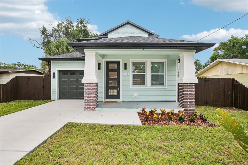 A light green house with a front porch, brick pillars, and a single-car garage — 3612 E CLIFTON STREET, TAMPA, FL