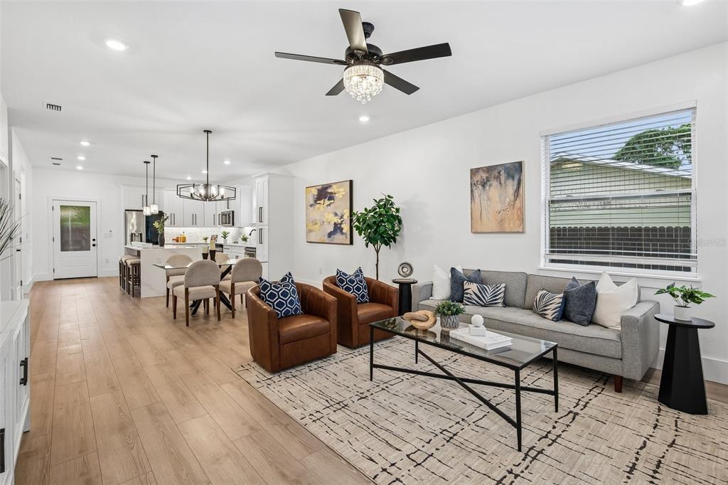 An open-concept living room and kitchen featuring light wood floors and a gray sofa — 3612 E CLIFTON STREET, TAMPA, FL
