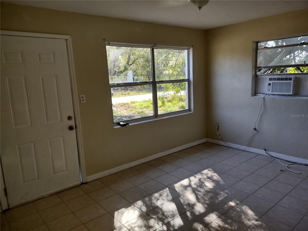 An interior room features light-colored walls, tiled flooring, a white door, and a window air conditioner — 157 E NORTHSIDE DRIVE UNIT 1, LAKE WALES, FL