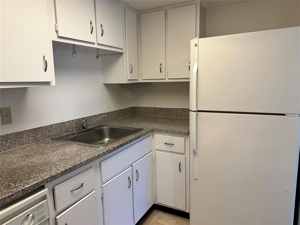 A kitchen features white cabinets, a stainless steel sink, and a white refrigerator — 2517 CAPER LANE UNIT 205, MAITLAND, FL