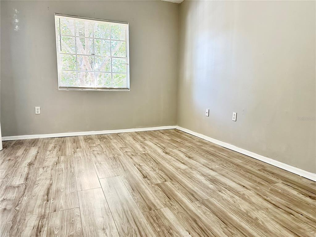An empty room features light gray walls, wood-look laminate flooring, and a single window — 2517 CAPER LANE UNIT 205, MAITLAND, FL