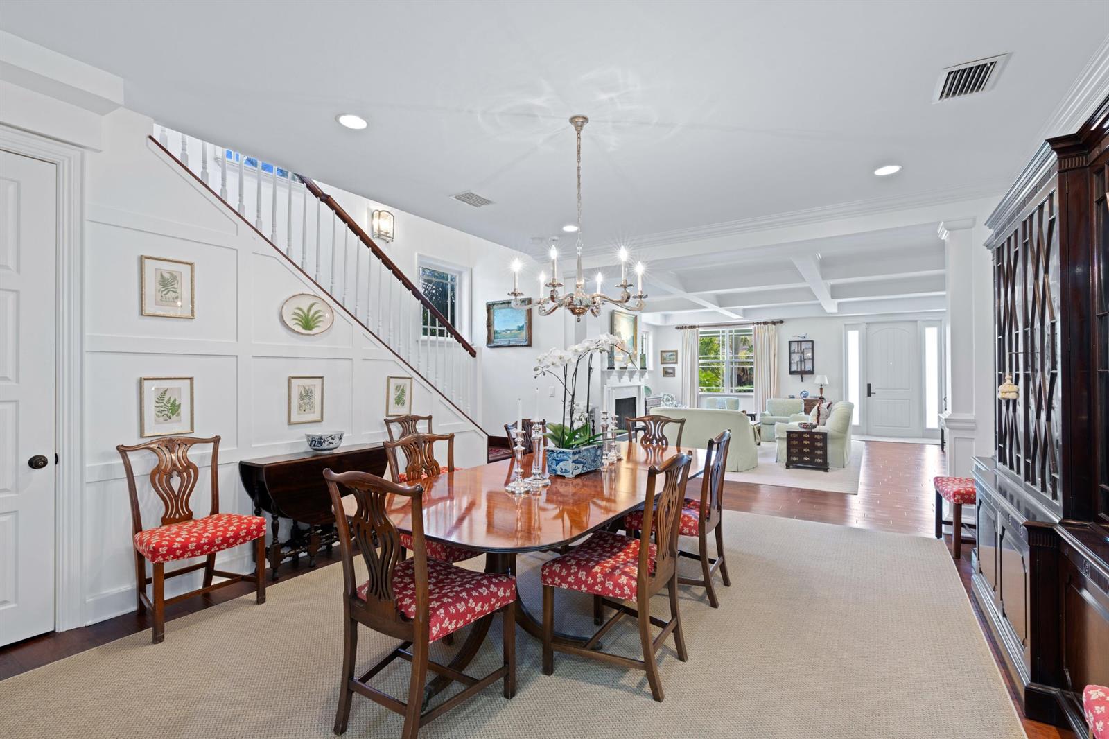 A dining room with a wooden table, chairs with red patterned cushions, and a staircase — 137 Cortez Road, West Palm Beach FL 33405, WEST PALM BEACH, FL