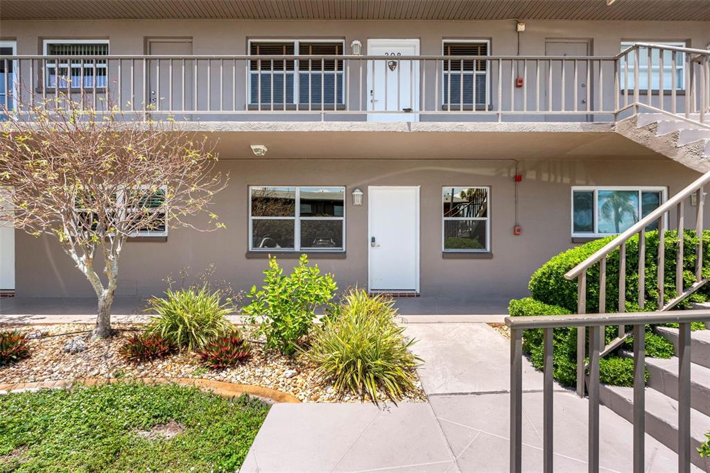 Exterior view of a two-story apartment building with a concrete walkway and metal railings — 1 GATESHEAD DRIVE UNIT B108, DUNEDIN, FL