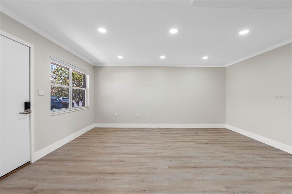 An empty room with light-colored walls, wood-look flooring, recessed lighting, and a single window — 1 GATESHEAD DRIVE UNIT B108, DUNEDIN, FL