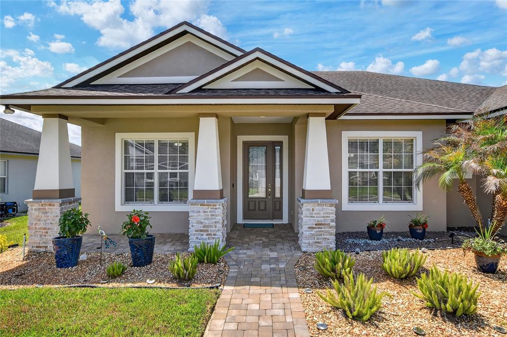 The exterior of a single-story house features a stone-accented porch, white columns, and landscaping — 3171 PEARLY DRIVE, LAKELAND, FL