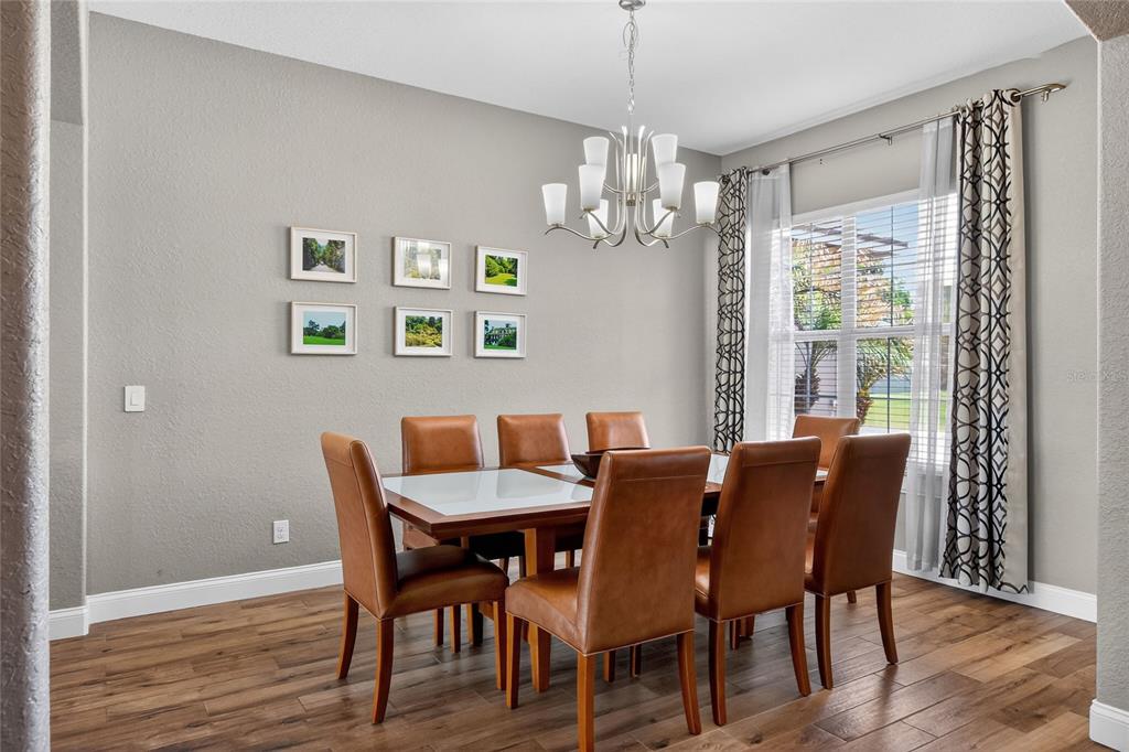 A dining room with a wooden table, leather chairs, a chandelier, and framed wall art — 3171 PEARLY DRIVE, LAKELAND, FL