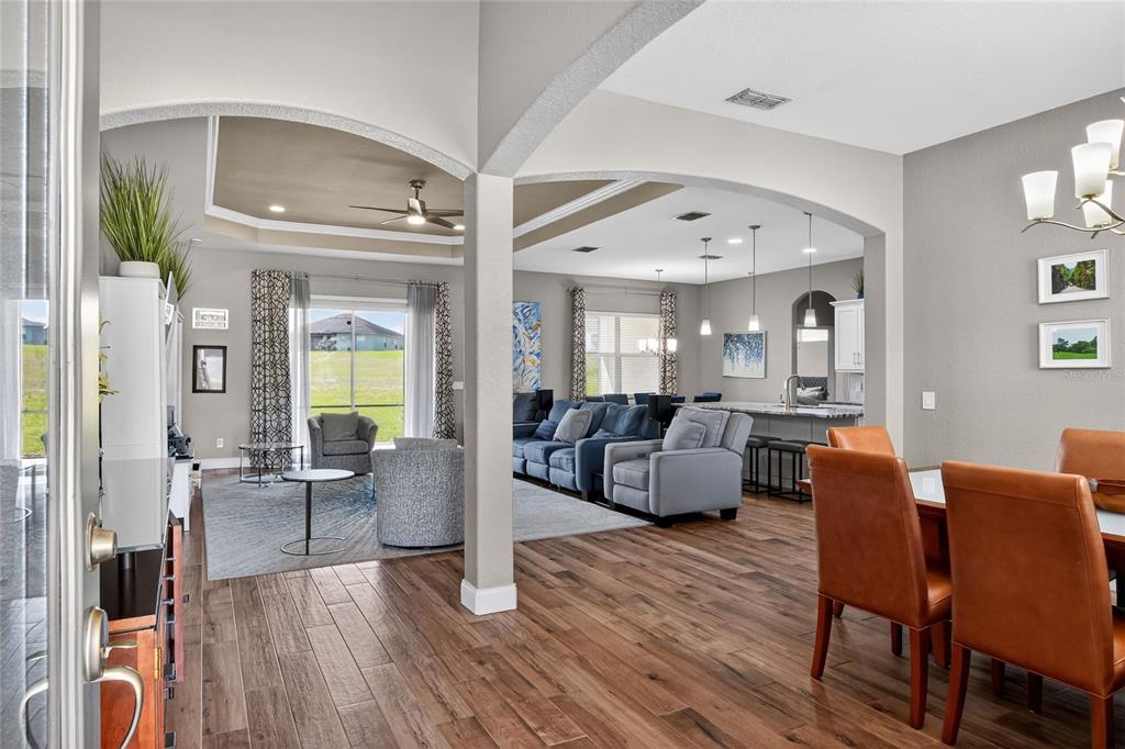 A view from an entryway into an open-concept living room and dining area with wood floors — 3171 PEARLY DRIVE, LAKELAND, FL