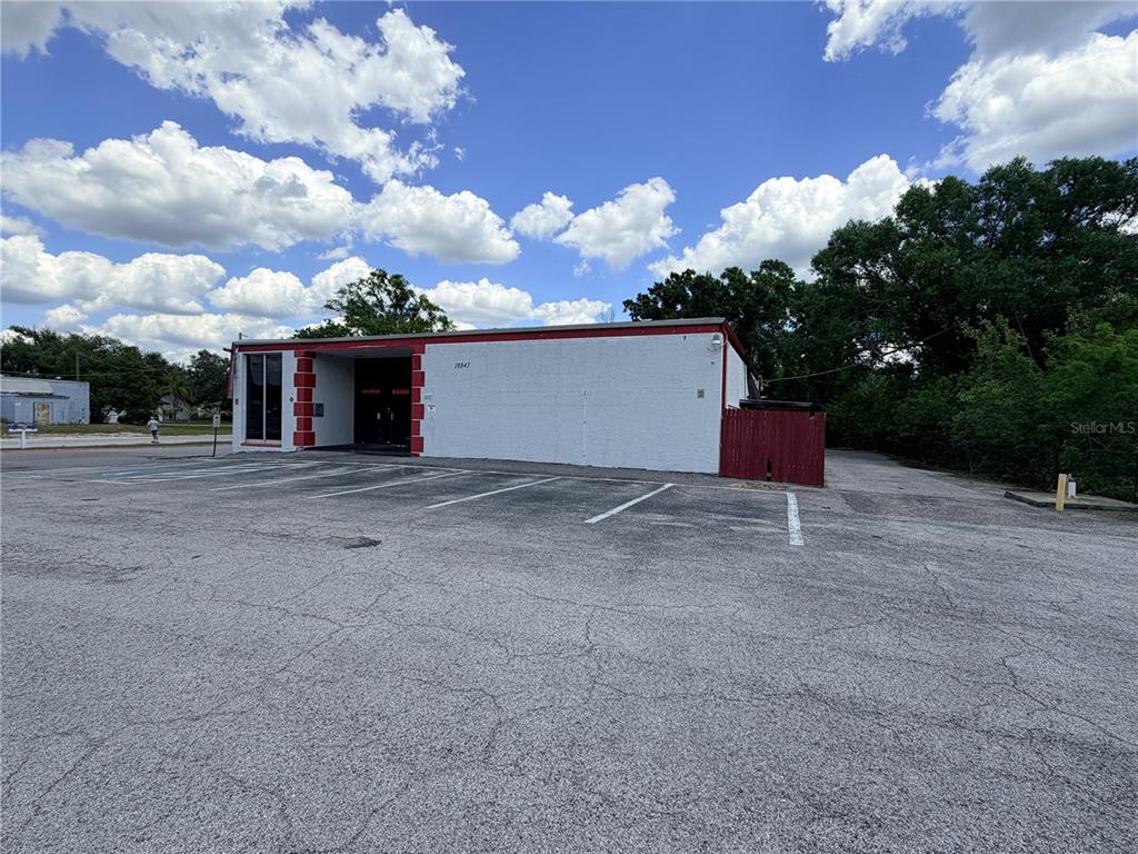 A white commercial building with red trim features a paved parking lot in front — 18843 N 41 HIGHWAY, LUTZ, FL