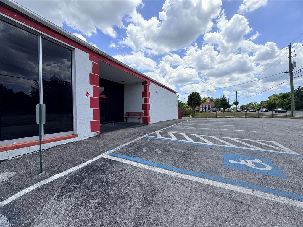 An exterior view of a commercial building with a handicap parking space and red accents — 18843 N 41 HIGHWAY, LUTZ, FL