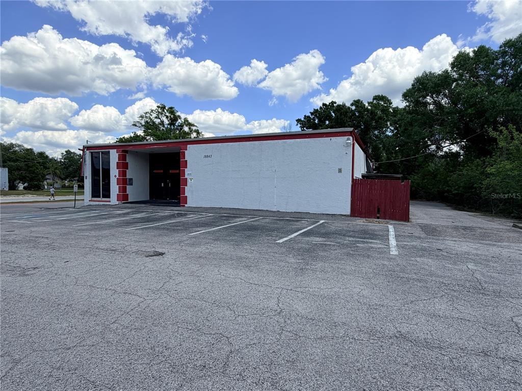 A white commercial building with red trim and a parking lot under a cloudy sky — 18843 N 41 HIGHWAY, LUTZ, FL