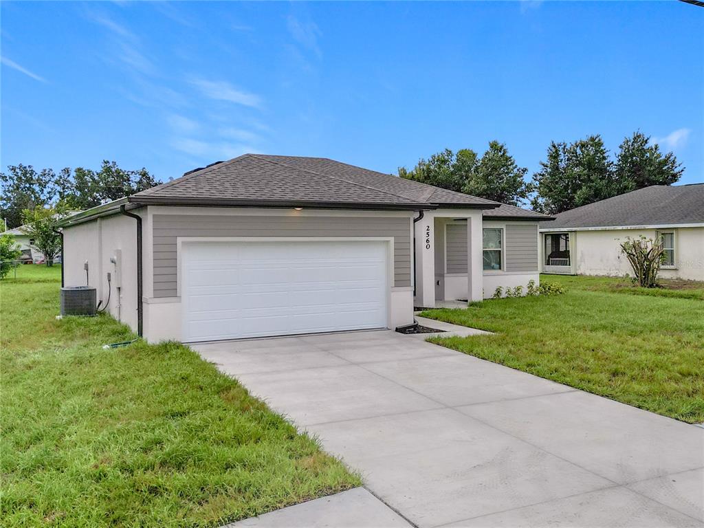 A single-story house with a white garage door, gray siding, and a concrete driveway — 2560 S BISCAYNE DRIVE, NORTH PORT, FL
