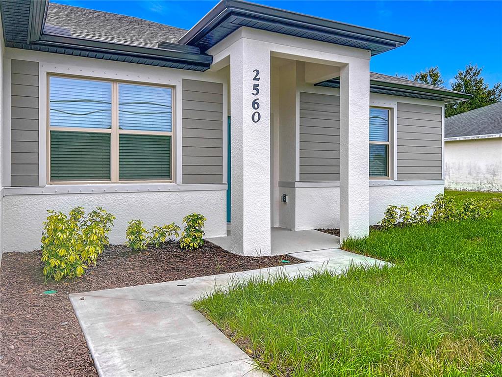 The exterior of a house features white stucco walls, gray horizontal siding, and a concrete walkway — 2560 S BISCAYNE DRIVE, NORTH PORT, FL