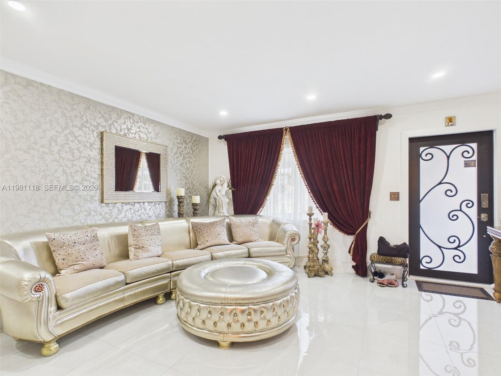 A living room features a metallic gold sofa, a matching ottoman, and deep red curtains — 9911 Haitian Dr, Cutler Bay FL 33189, CUTLER BAY, FL