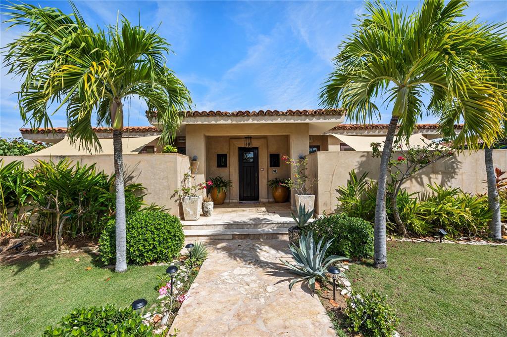 A stone walkway leads to the front entrance of a stucco home with palm trees — 2 OCEAN GOLF VILLA ROYAL ISABELA, ISABELA, PR