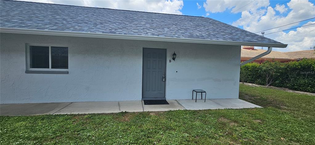 A gray door labeled B is centered on the exterior wall of a white building — 1205 ACADEMY BOULEVARD UNIT B, CAPE CORAL, FL