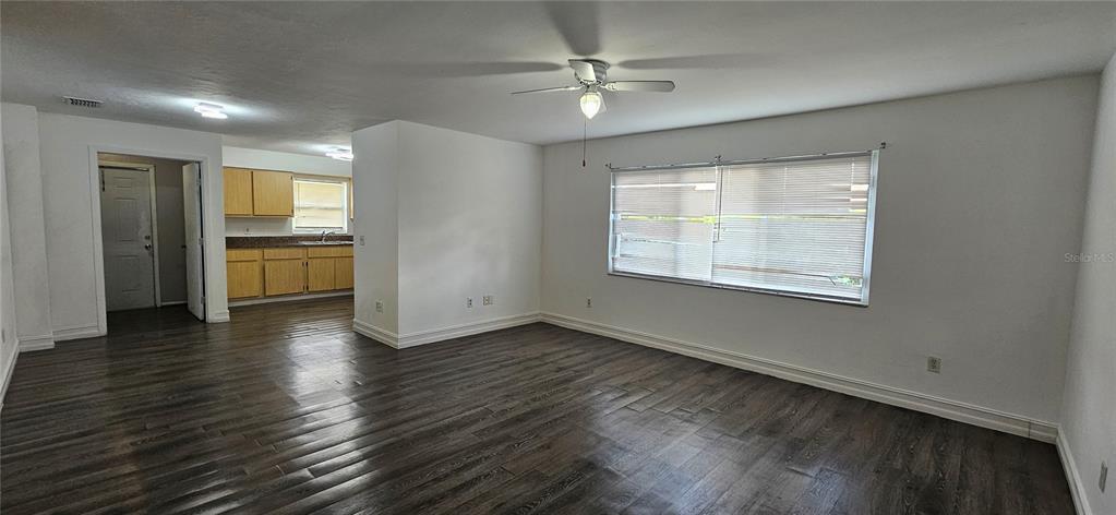 A living room with dark wood-look flooring, white walls, and a ceiling fan — 1205 ACADEMY BOULEVARD UNIT B, CAPE CORAL, FL