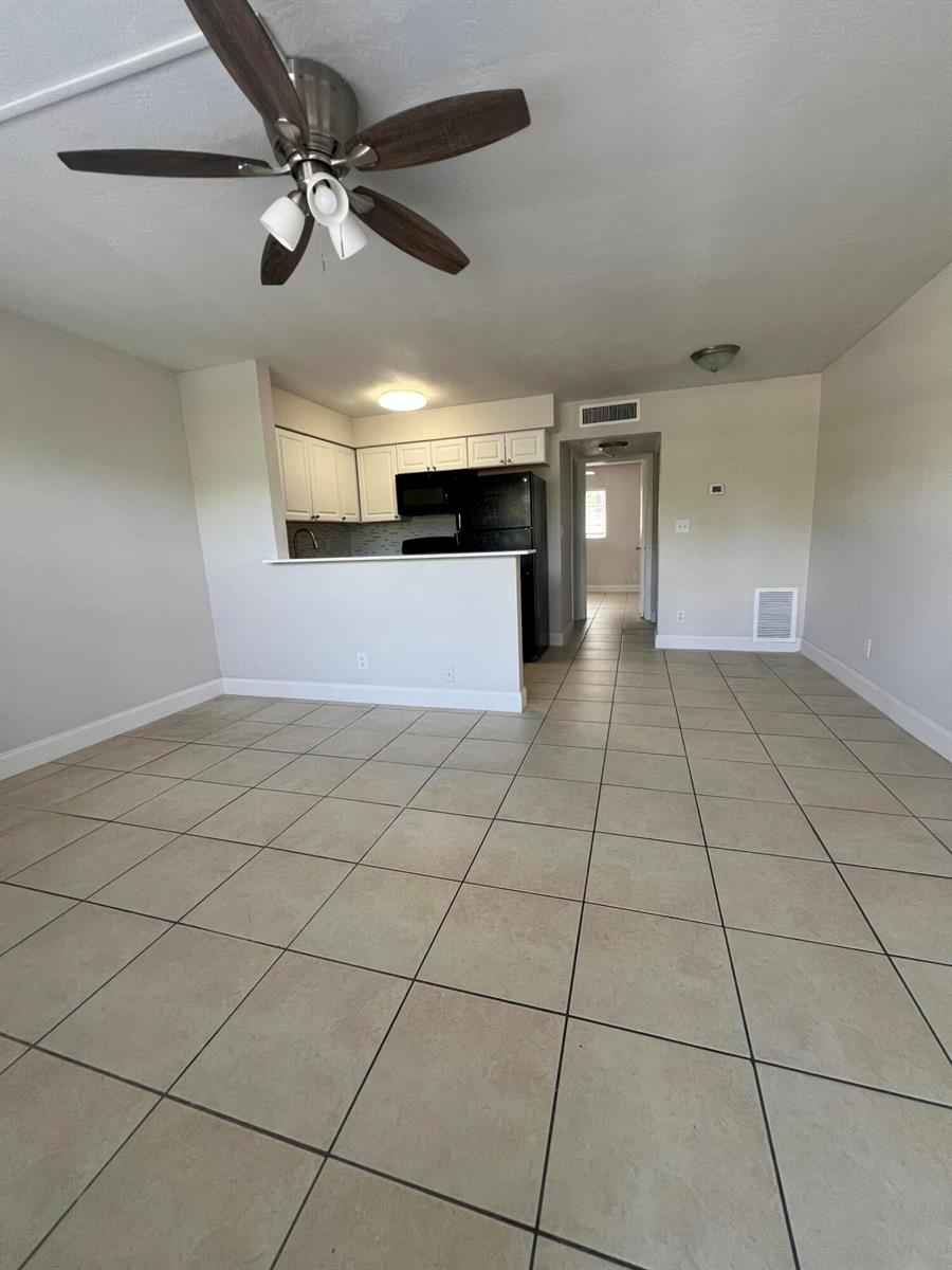 An open-concept living area with tile flooring, a ceiling fan, and a kitchen pass-through — 4670 NE 5th Avenue # 5, Boca Raton FL 33431, BOCA RATON, FL