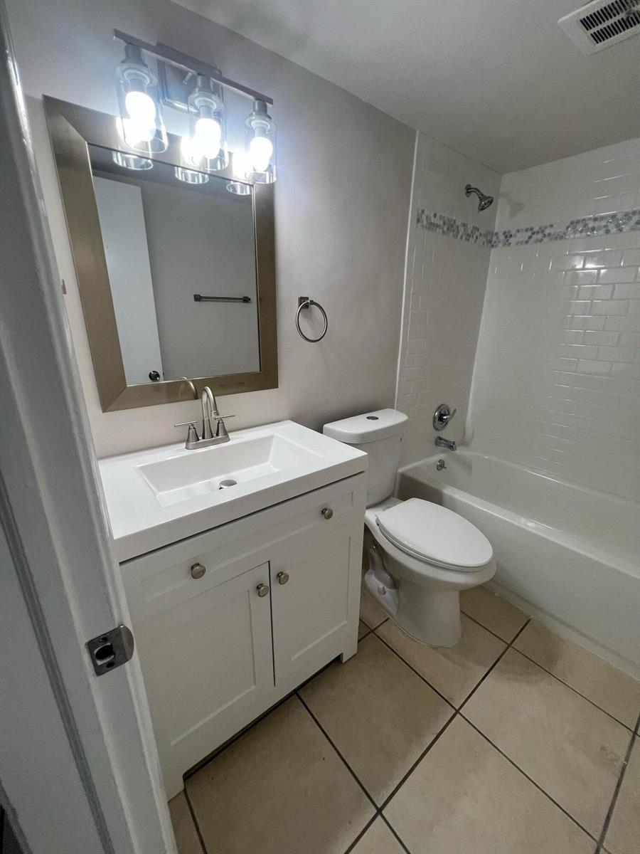 A bathroom features a white vanity, a mirror, a toilet, and a tiled shower-tub combo — 4670 NE 5th Avenue # 5, Boca Raton FL 33431, BOCA RATON, FL