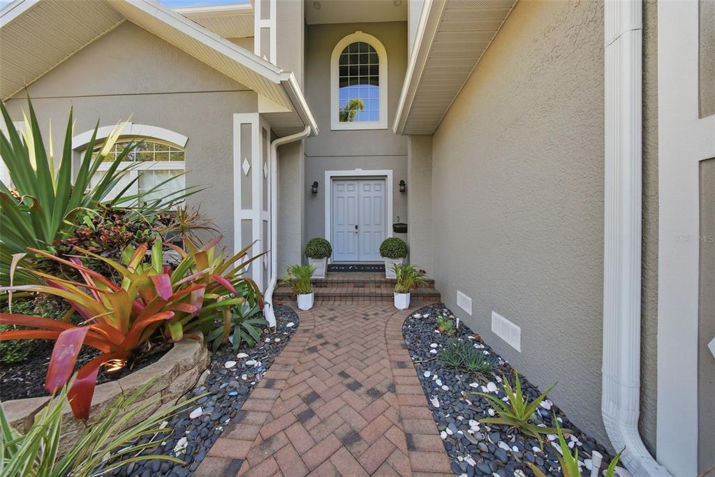 A brick walkway leads to the double front doors of a house with stucco siding — 234 36TH AVENUE NE, ST PETERSBURG, FL