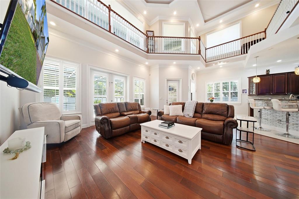 A spacious living room features high ceilings, a balcony, hardwood floors, and leather furniture — 234 36TH AVENUE NE, ST PETERSBURG, FL