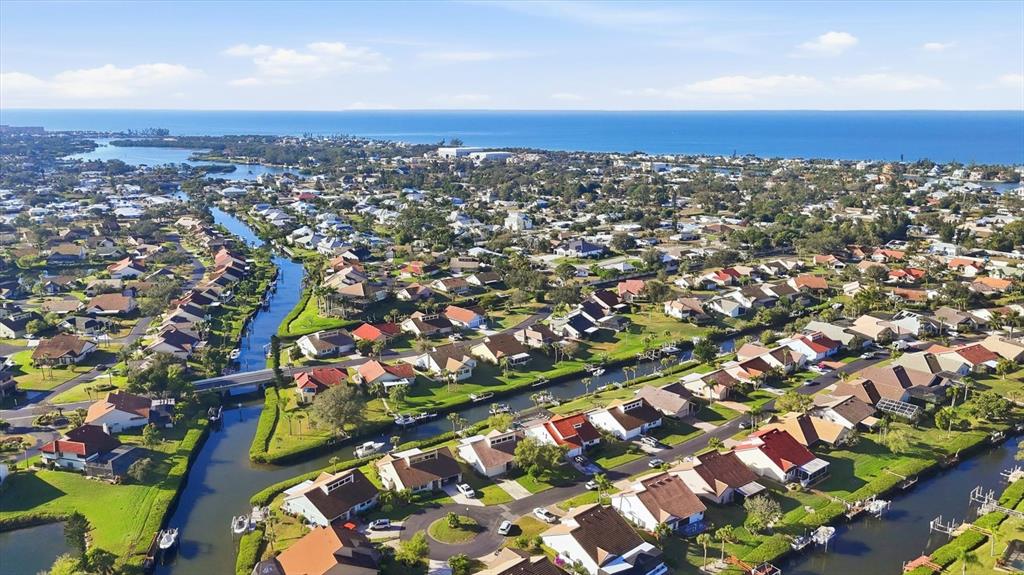 An aerial view shows a residential neighborhood with houses situated along winding canals near the ocean — 139 INLETS BOULEVARD UNIT 139, NOKOMIS, FL