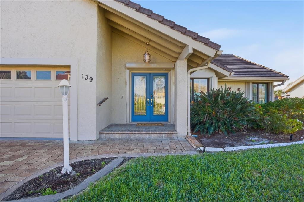 A single-story house exterior features a blue double front door, a garage, and landscaping — 139 INLETS BOULEVARD UNIT 139, NOKOMIS, FL