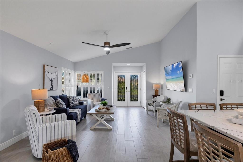A bright living room features light gray walls, tile flooring, a vaulted ceiling, and furniture — 139 INLETS BOULEVARD UNIT 139, NOKOMIS, FL