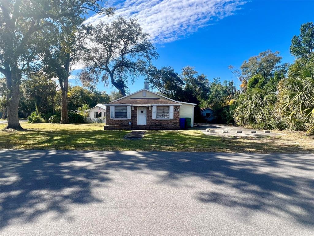 A single-story house with a brick facade and a front yard sits under a blue sky — 160 N 4TH STREET, LAKE MARY, FL