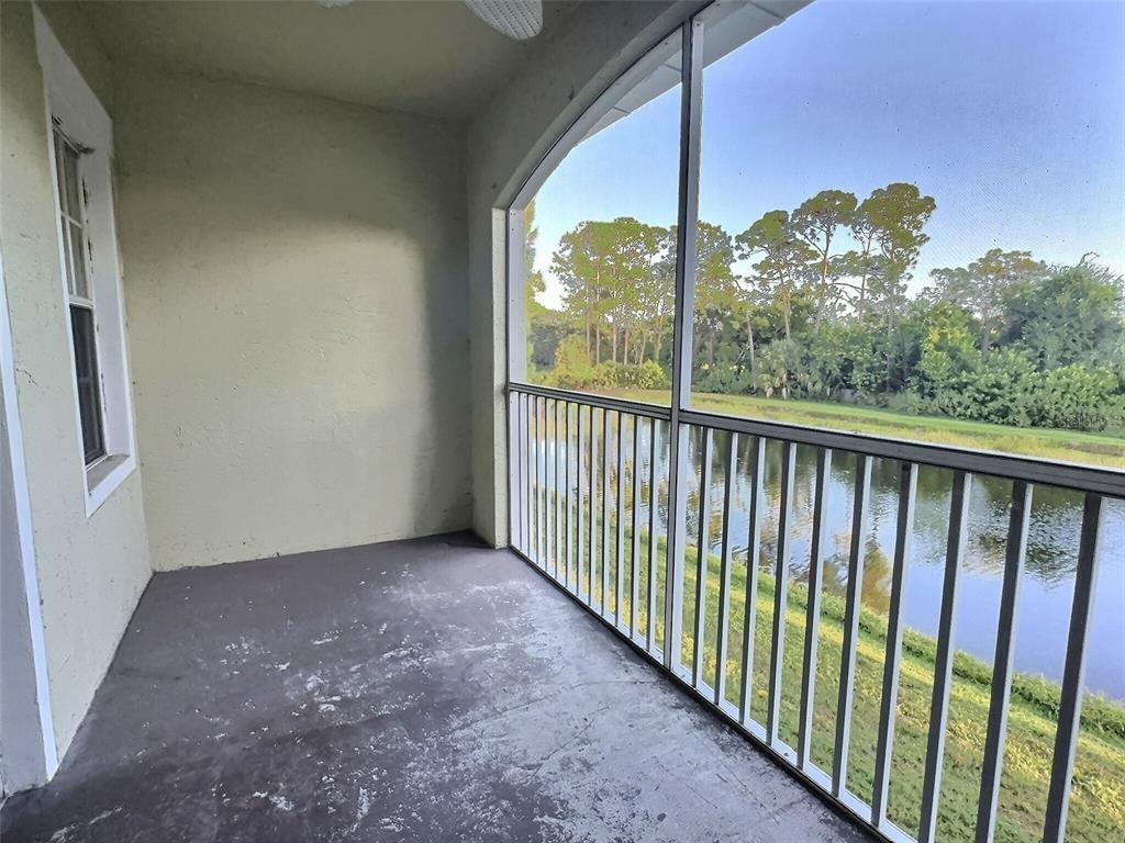 A screened-in balcony with a concrete floor overlooks a pond and trees — 4751 TRAVINI CIRCLE UNIT 4-105, SARASOTA, FL