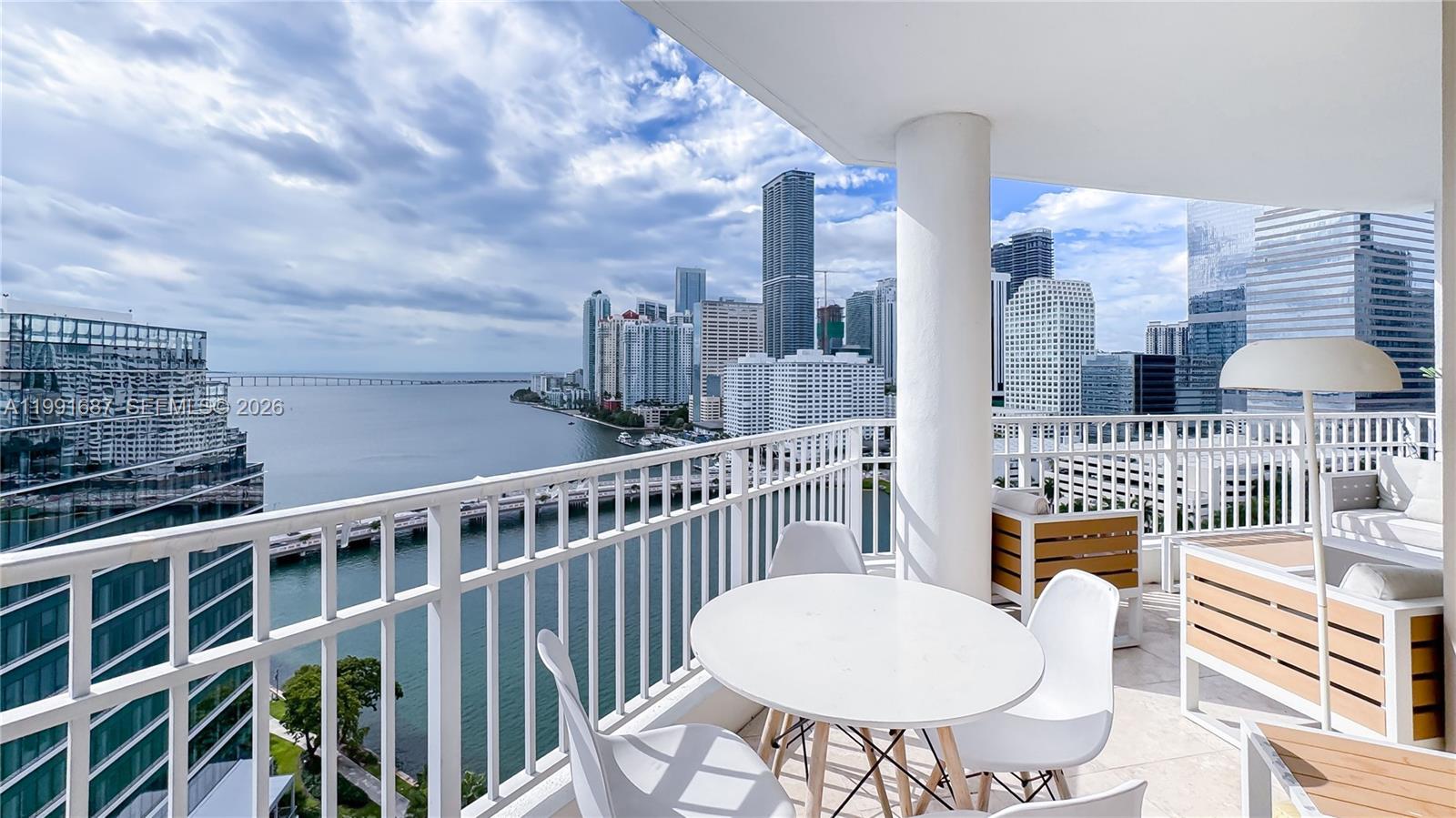 A balcony with outdoor furniture overlooks a bay and a city skyline — 701 Brickell Key Blvd # 1912, Miami FL 33131, MIAMI, FL